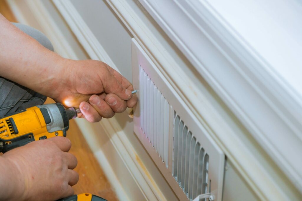 Person installing an HVAC cover in a wall.